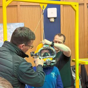 One pupil tries on a diving helmet at one of the stands 